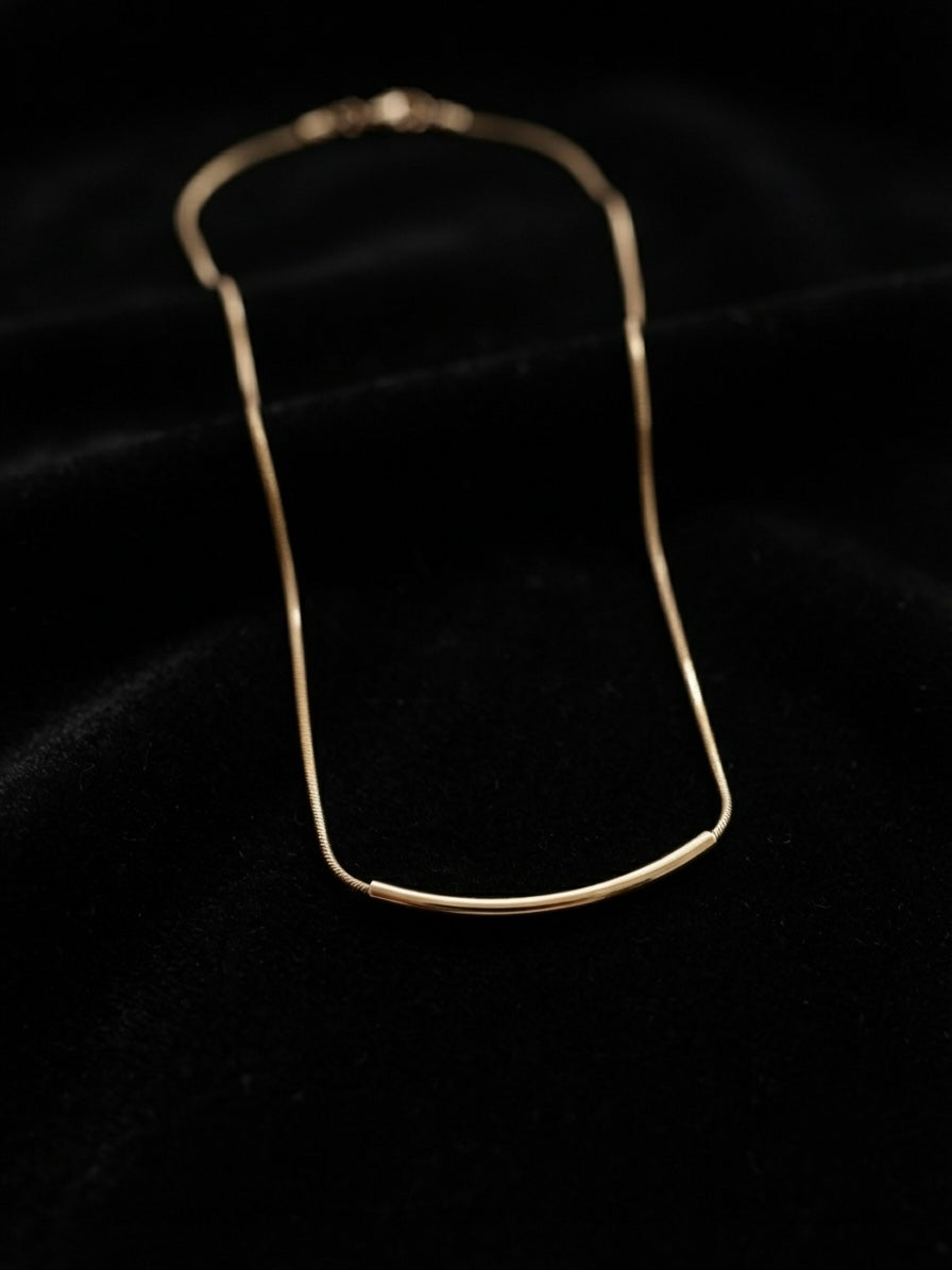 Minimalist gold curved bar necklace.