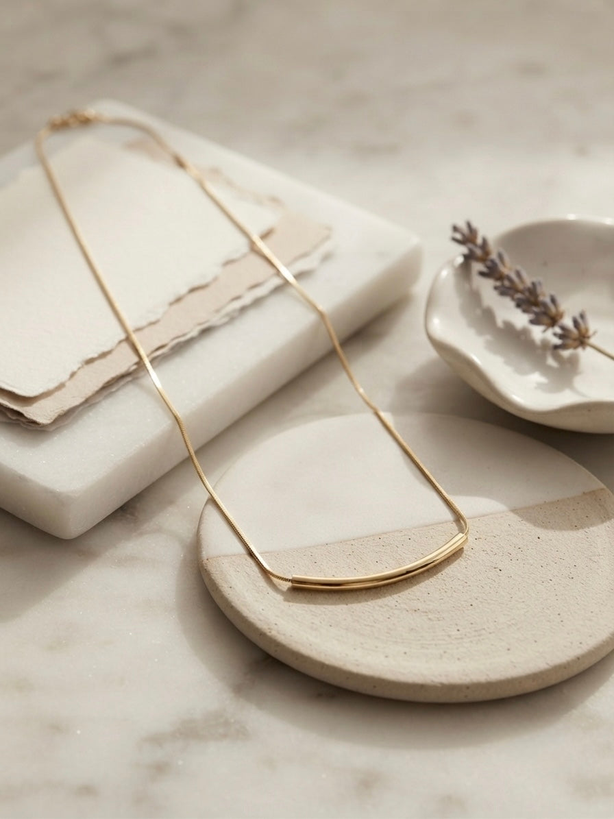 Minimalist gold curved bar necklace.