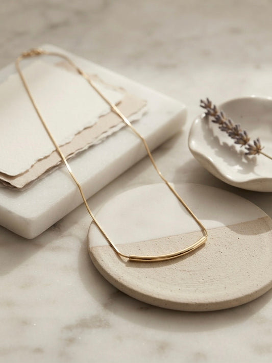 Minimalist gold curved bar necklace.