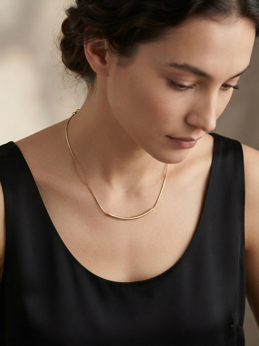 Minimalist gold curved bar necklace.