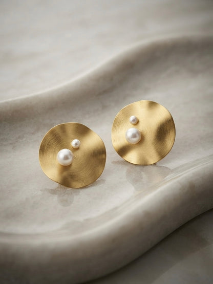 Modern concentric gold disc pearl studs.