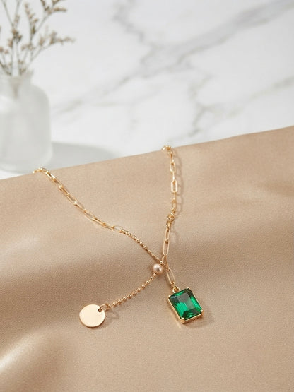 Gold dual-chain necklace with emerald drop.