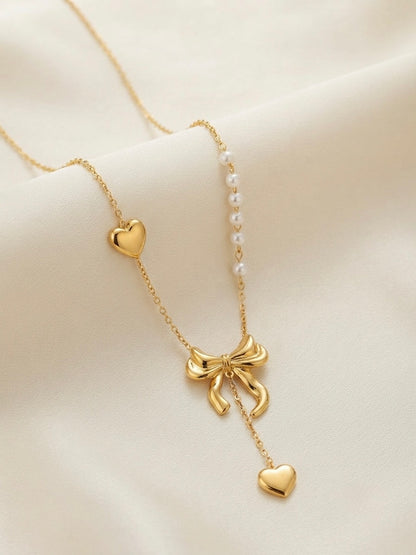 Gold bow and pearl asymmetric heart necklace.