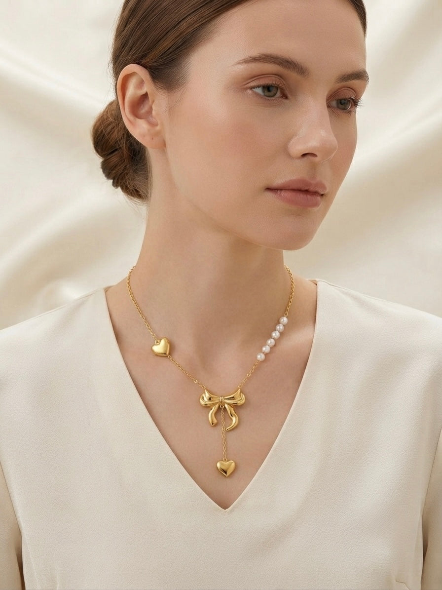 Gold bow and pearl asymmetric heart necklace.