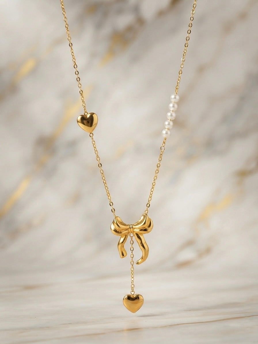 Gold bow and pearl asymmetric heart necklace.