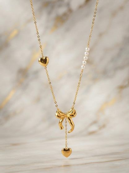 Gold bow and pearl asymmetric heart necklace.